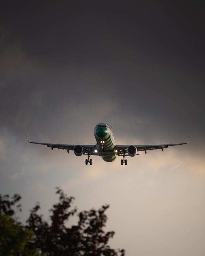A green airplane descends through a cloudy sky, captured in Hamburg, Germany.