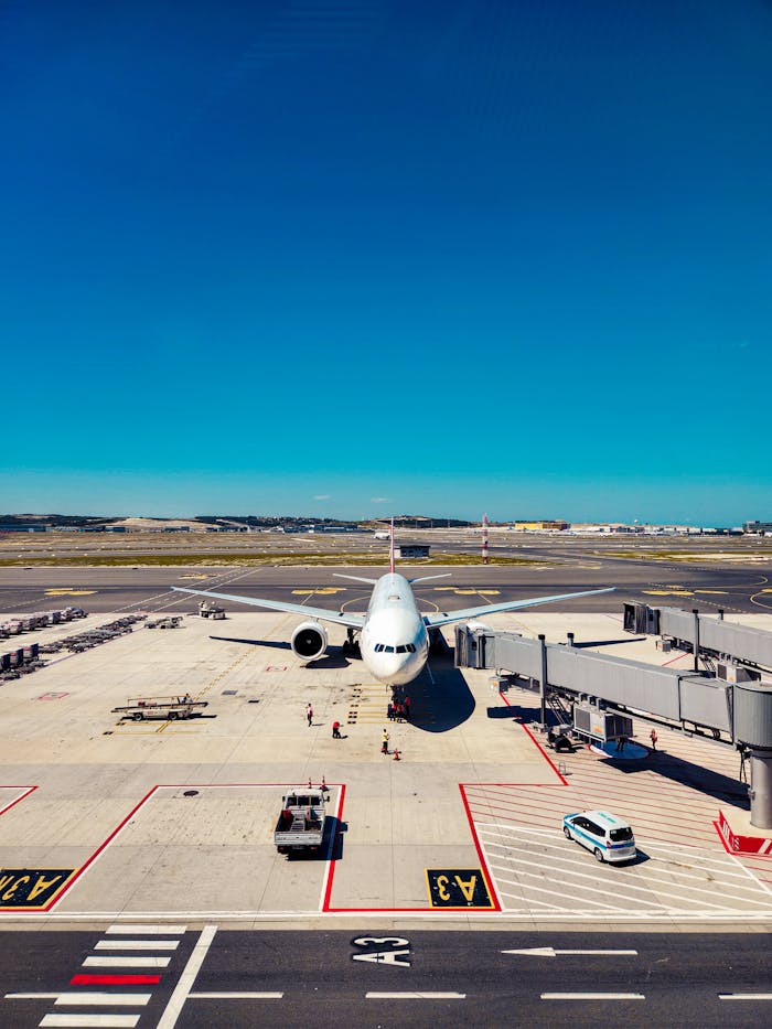 Airplane parked at airport gate, ready for passenger boarding under clear blue skies.