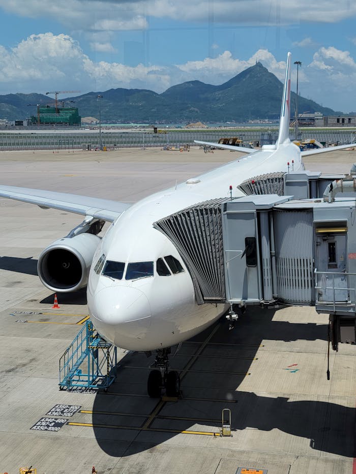 Commercial airplane docked at a boarding gate with mountains in the background.